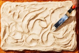 Silky frosting being applied to a cake with an offset spatula